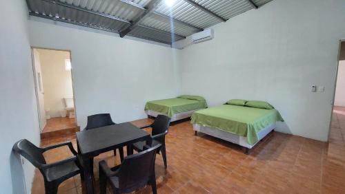 um quarto com duas camas e uma mesa e cadeiras em Villa Santos em Escuintla