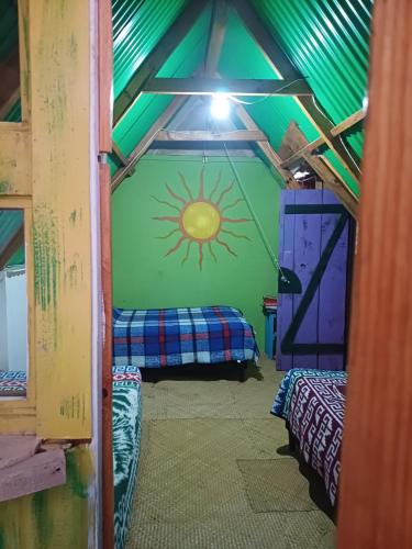 a room with a green wall with a sun painted on it at Las Cabañas De Mike in San Juan La Laguna