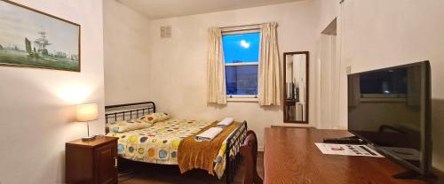 a small bedroom with a bed and a television at The Greenwich Pensioner Guesthouse in London