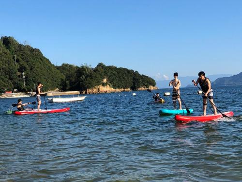 a group of people on paddle boards in the water at East Villa Shimanami Mukaishima seafront in Onomichi