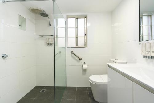 a bathroom with a toilet and a glass shower at Sapphire Waters Motor Inn in Merimbula