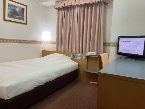 Hotel Alpha-One Iwakuni في إواكوني: غرفة في الفندق بها سرير ومكتب وبه جهاز كمبيوتر