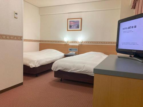a hotel room with two beds and a flat screen tv at Hotel Alpha-One Iwakuni in Iwakuni