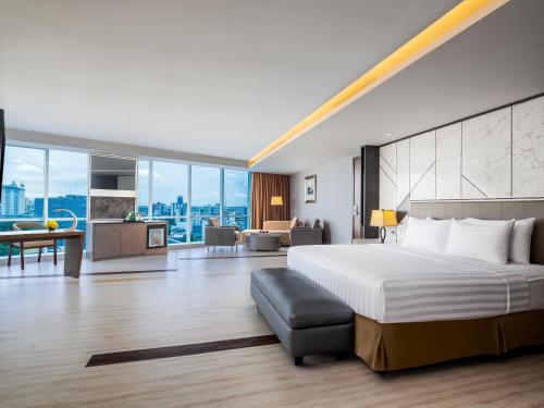 a bedroom with a large bed and a living room at ASTON Makassar Hotel & Convention Center in Makassar
