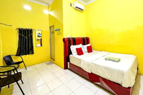 une chambre avec un lit dans une chambre jaune dans l'établissement Hotel Alam Lestari RedPartner, à Palembang