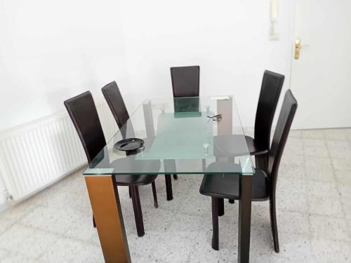 uma mesa de jantar de vidro com quatro cadeiras pretas em Joli Appartment A Zitouna 2 em Port El Kantaoui