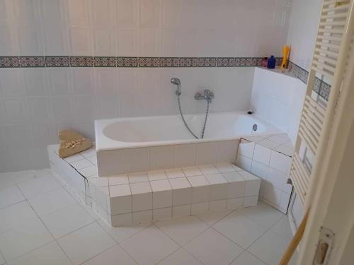 a white bathroom with a tub with a shower at Joli Appartment A Zitouna 2 in Port El Kantaoui