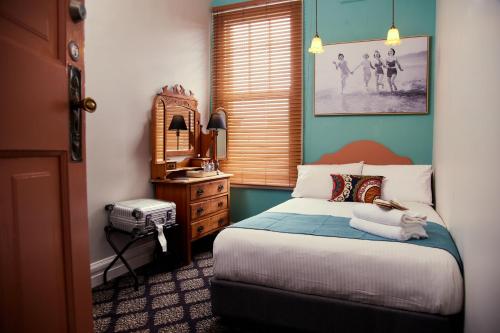um quarto com uma cama com um gato deitado sobre ela em The Australian Heritage Hotel em Sydney