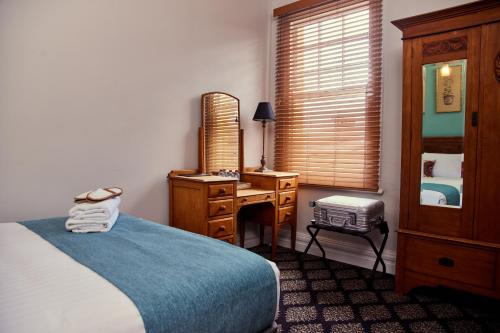 a bedroom with a bed and a desk with a mirror at The Australian Heritage Hotel in Sydney