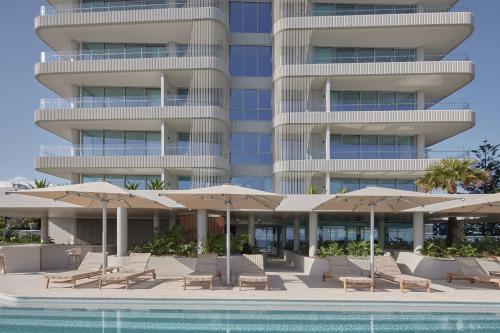 a hotel with chairs and umbrellas next to a swimming pool at Kirra Point Holiday Apartments in Gold Coast