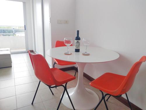 una mesa blanca con 2 copas de vino y sillas rojas en Hermoso Departamento Unico en La Plata