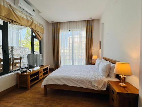 峴港的住宿－Qi Villa My Khe Beach，一间卧室设有一张床、一台电视和一个窗口。