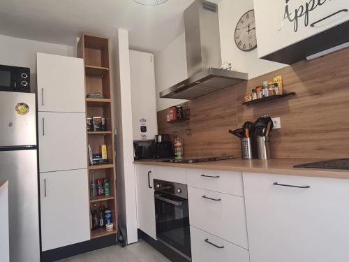 une cuisine avec des armoires blanches et un réfrigérateur noir dans l'établissement Collioure: Superbe T3 avec terrasse, face à la mer et parking - FR-1-309-376, à Collioure