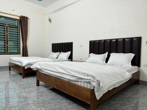 2 camas en una habitación con sábanas y almohadas blancas en Hotel Minh Thắng, en Phủ Nho Quan
