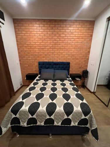 un letto bianco e nero in una stanza con muro di mattoni di Cómodo céntrico y acogedor apartamento a Tarija