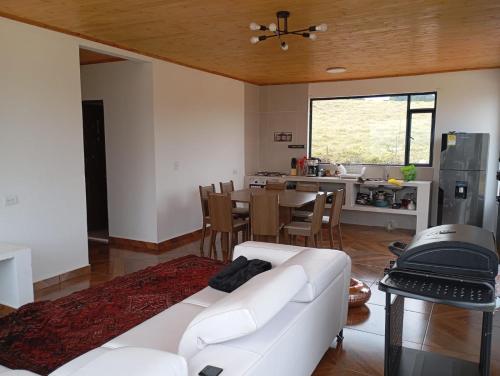a living room with a white couch and a kitchen at Finca Siberia, Sisga in Tilatá