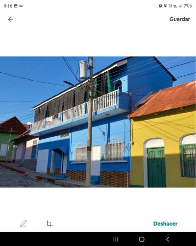 フローレスにあるHostal Doña Gladysの青と黄色の建物(バルコニー付)