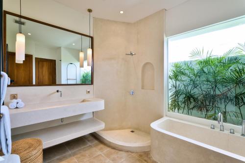 a bathroom with a tub and a large window at Elena Villa by Hombali in Tanah Lot