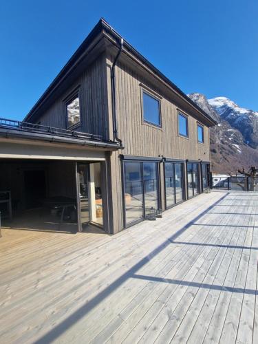 a large building with a deck with mountains in the background at Flo Bellevue in Stryn
