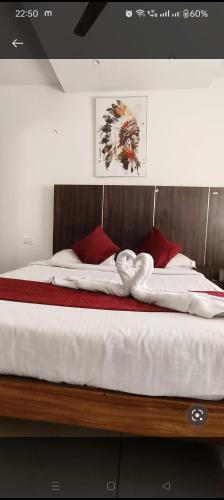 een bed met witte lakens en rode kussens erop bij Quince mysore in Mysore