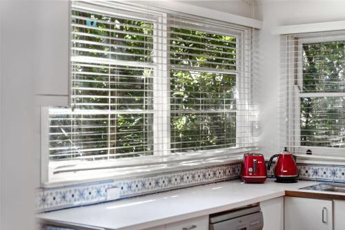 a kitchen with two red appliances and two windows at King Parrot in Pearl Beach