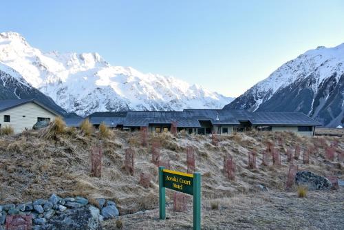 a sign in front of a building with mountains in the background at Aoraki Court Motel in Mount Cook Village