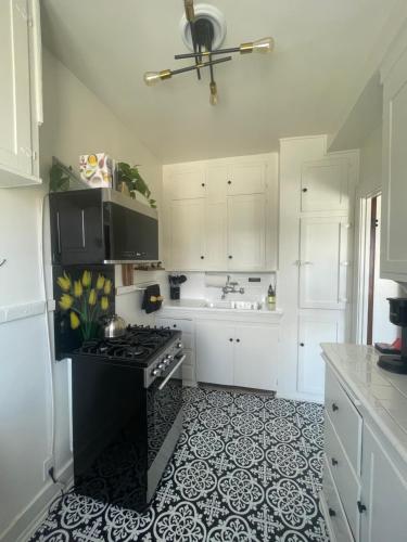a kitchen with white cabinets and a black stove at STUDIO- Sleeps 2 with Queen Mary and Ocean View in Long Beach