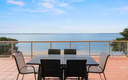 a table and chairs on a balcony with a view of the beach at Phillip Island Escape on the Esplanade in Cowes