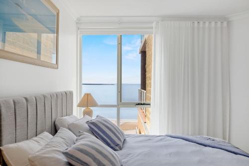 een slaapkamer met een bed en uitzicht op de oceaan bij Penthouse Esplanade Cowes - Beach Front - Sea View in Cowes