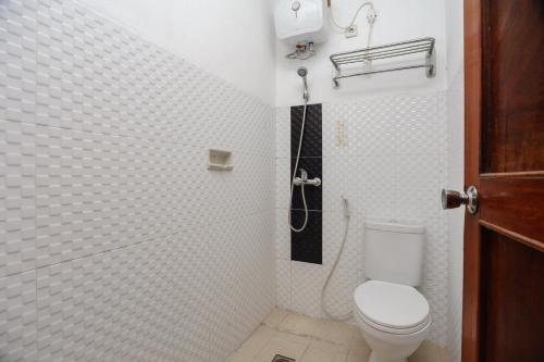 a white tiled bathroom with a toilet and a shower at RedDoorz syariah near AEON Mall Tanjung Barat in Jakarta