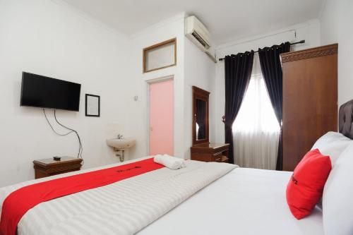 een slaapkamer met een groot wit bed met rode kussens bij RedDoorz syariah near AEON Mall Tanjung Barat in Jakarta