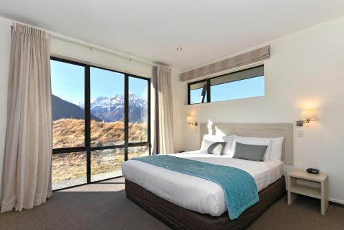 a bedroom with a large bed and large windows at Aoraki Court Motel in Mount Cook Village