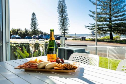 a plate of food and a bottle of wine on a table at La Ronde One - Unit 1 - oceanstays in Yamba