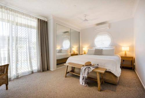 a bedroom with a bed and a table and windows at La Ronde One - Unit 1 - oceanstays in Yamba
