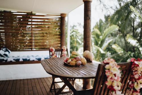a wooden table with a bowl of fruit on a porch at Tai Marino Beach Bungalows in Amuri