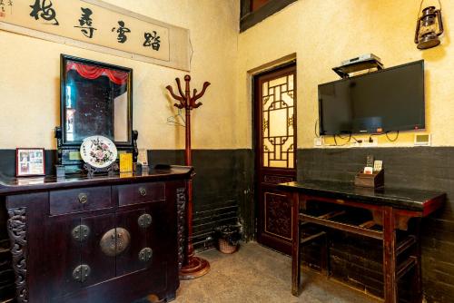 a living room with a tv and a table and a table sidx sidx at Pingyao Ji Family Courtyard Inn in Pingyao