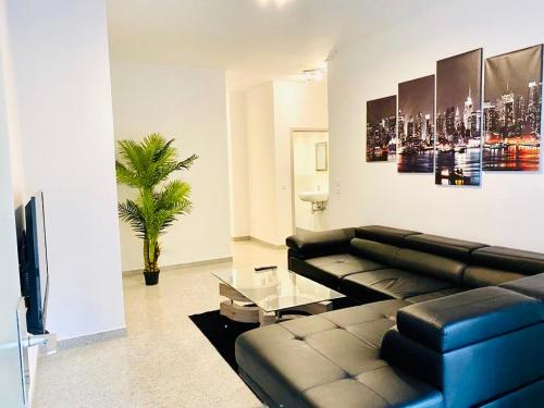 a living room with a black leather couch and a tv at Luxury Premium Apartments in Bonn