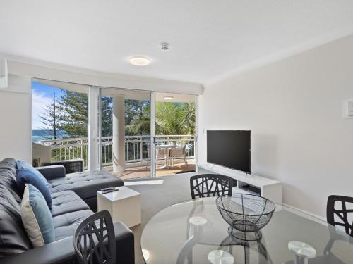 a living room with a couch and a television at ULTIQA Burleigh Mediterranean Resort in Gold Coast