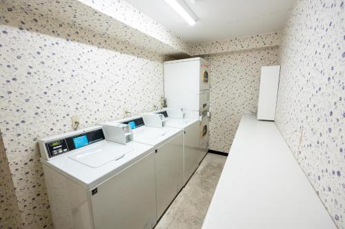 a kitchen with white cabinets and a white refrigerator at ユースホステルソノママ in Kofu