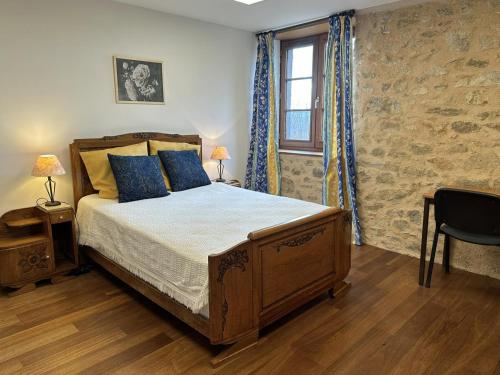 een slaapkamer met een bed met blauwe kussens en een raam bij La murette in Solignac