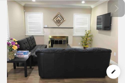 a living room with a black couch and a fireplace at New! Cozy Gated 3BR, 2BA Vacation Home in Rosemead