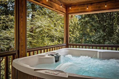 - une baignoire dans une chambre avec 2 fenêtres dans l'établissement Secluded, Views, Relax Hot Tub Fun Arcade Gameroom, à Sevierville