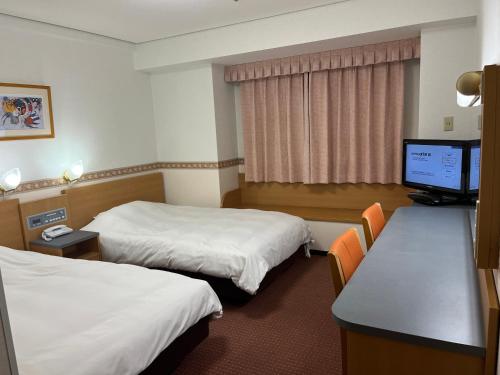 防府市にあるホテルアルファーワン防府のベッド2台、薄型テレビが備わるホテルルームです。