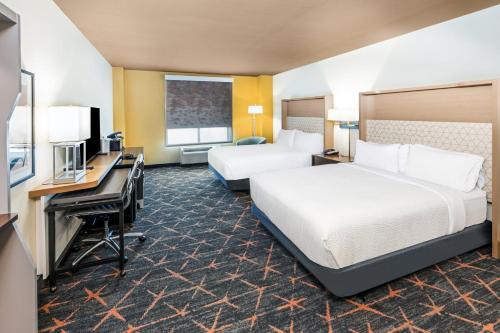 a hotel room with two beds and a desk at Holiday Inn & Suites Stillwater-University West by IHG in Stillwater