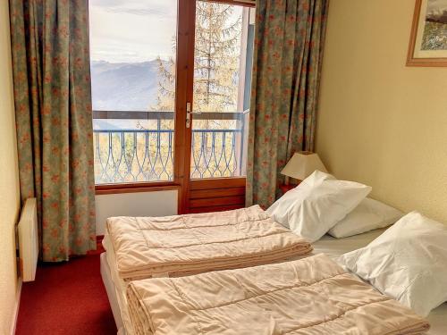 a bedroom with two beds in front of a window at Appartement Les Arcs 1800, 3 pièces, 6 personnes - FR-1-346-571 in Bourg-Saint-Maurice