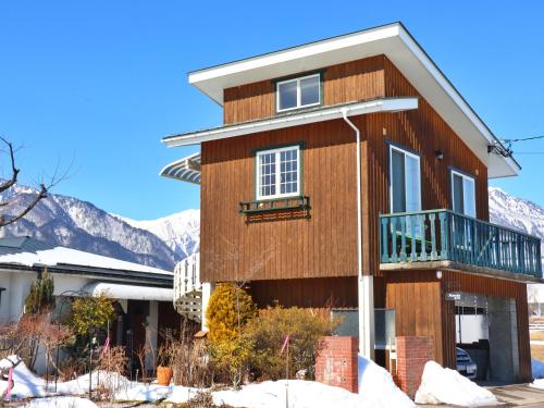 a house with snowy mountains in the background at コテージ野の香 in Omachi