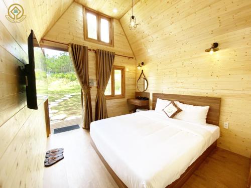 ein Schlafzimmer mit einem Bett in einer Holzhütte in der Unterkunft Kim Resort - Khu Nghĩ Dưỡng Rừng Lá Kim in Da Lat