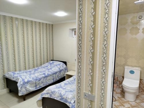 a small room with two beds and a toilet at Quba ALFA-M Motel in Quba