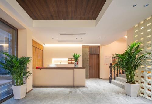 an office lobby with a reception desk and two plants at Lingxi Riverview Boutique Homestay - Phoenix Ancient Town in Fenghuang