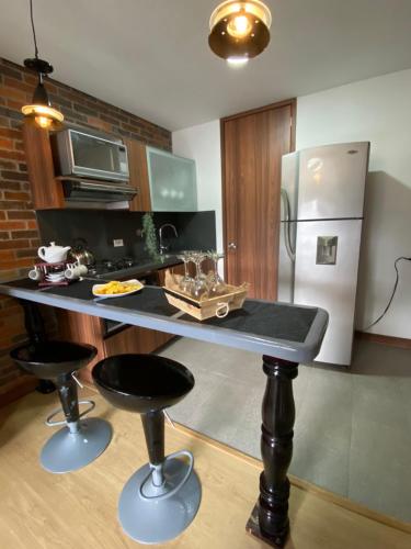 a kitchen with a table with two stools and a refrigerator at Apartamento en Retiro in El Retiro